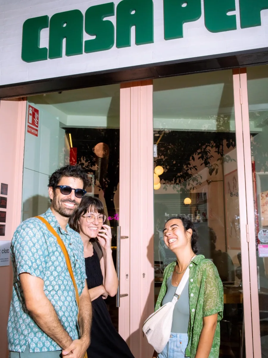 Tres clientes riéndose en la puerta de Casa Pepi, bajo el rótulo verde del local