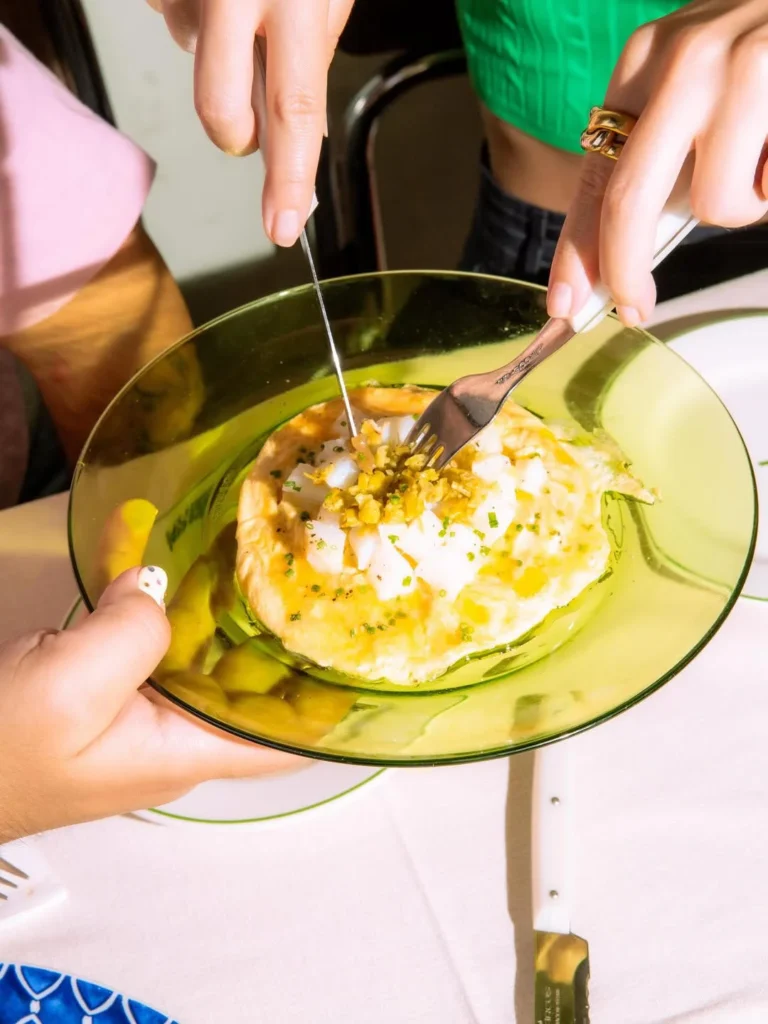 Tortilla con alioli y encurtidos en un plato verde en Casa Pepi